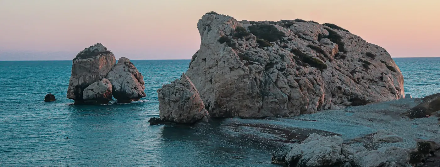 Aphrodite's Rock (Petra tou Romiou) in a calm sea at dusk