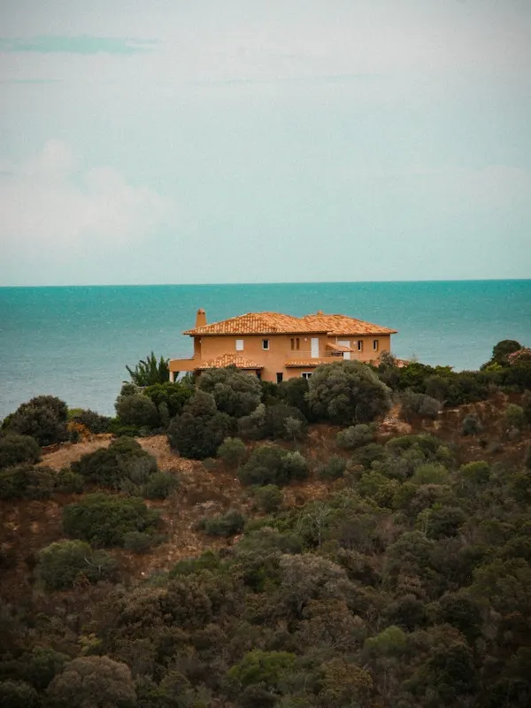 Villa with a terracotta roof on a green hillside above the sea